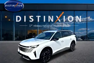 Peugeot 5008 Hybrid blanc en 3/4 avant droit, avec jantes noires et toit noir, devant une vitrine Distinxion.