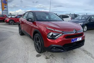 Citroën C4 Rouge Elixir en 3/4 avant droit avec jantes alliage noires et calandre distinctive sur parking.
