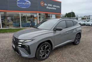 Vue 3/4 avant droite d’un Hyundai Tucson gris métallisé N Line avec jantes alliage 19 pouces et vitres teintées.