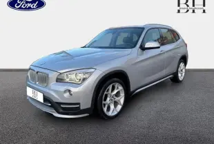 BMW X1 xDrive25dA 2014 en Mineralgrau, vue 3/4 avant droit avec jantes alu et phares bi-xénon allumés