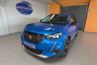 Peugeot 2008 bleu en 3/4 avant droit, avec calandre noire et jantes alliage bicolores, en intérieur showroom.