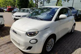 Fiat 500 électrique blanche vue 3/4 avant droit, avec phares ronds et calandre épurée distinctive.