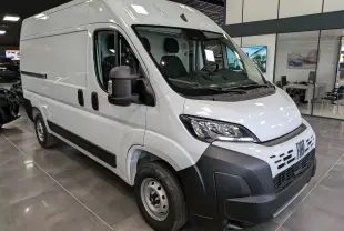Fiat Ducato Fourgon blanc en vue 3/4 avant droit, avec calandre noire et rétroviseurs larges visibles en intérieur showroom.