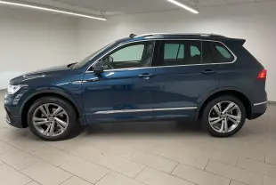 Volkswagen Tiguan 2024 bleu Nightshade en profil droit, avec jantes alliage et attelage escamotable visible à l'arrière.