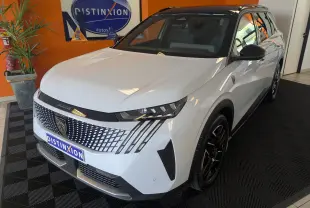 Peugeot 5008 Hybrid 145 GT blanc Okenite avec toit noir, vue 3/4 avant droit en intérieur showroom.