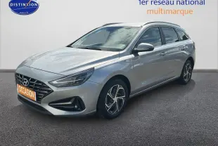 Hyundai i30 SW gris clair vue 3/4 avant droit avec jantes alliage 17 pouces sur fond neutre.