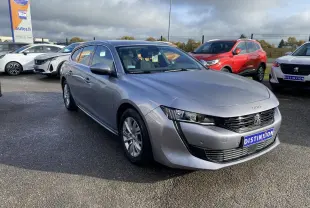 Peugeot 508 SW gris Artense vue 3/4 avant droit sur parking avec calandre noire et jantes alu.