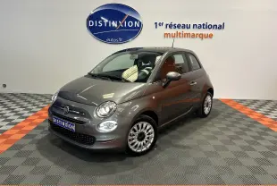 Vue 3/4 avant d'une Fiat 500 grise avec toit panoramique, dans un showroom au sol gris et orange.