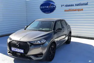 DS3 Crossback gris foncé en 3/4 avant droit, avec calandre noire et jantes sombres, stationné devant un mur blanc.