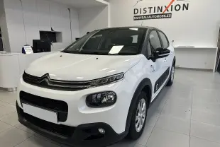 Citroën C3 blanc vue 3/4 avant droit en intérieur, avec protections latérales noires et jantes acier.