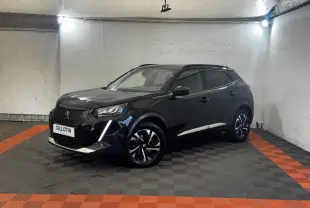 Peugeot 2008 noir en 3/4 avant droit, avec jantes alliage bicolores et feux LED distinctifs, stationné en intérieur.