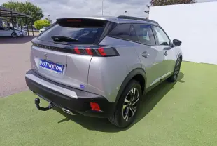Vue 3/4 arrière droite d'un Peugeot 2008 gris métallisé avec barres de toit noires et attelage visible.