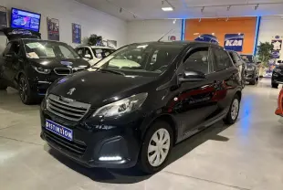 Peugeot 108 noir vue 3/4 avant droit en intérieur, avec feux diurnes allumés et calandre chromée visible.