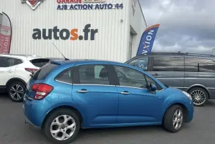 Profil côté droit d'une Citroën C3 bleue 2011 avec enjoliveurs 15'' Asterodea, stationnée devant un garage autos.fr.
