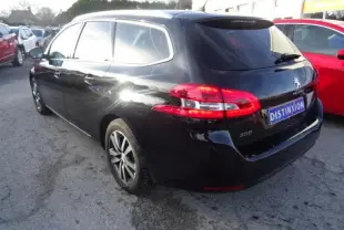 Peugeot 308 SW noire vue en 3/4 arrière droit, avec feux arrière allumés et jantes alliage visibles.