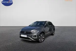 Volkswagen T-Roc gris en 3/4 avant droit, avec barres de toit noires et jantes distinctives.