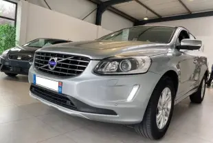 Vue 3/4 avant droite d'un Volvo XC60 argenté avec calandre chromée et phares halogènes en showroom.