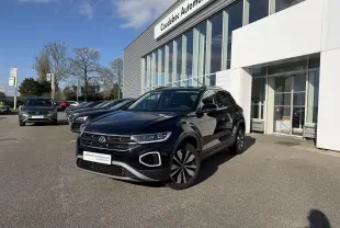 Volkswagen T-Roc noir en 3/4 avant droit, stationné devant un showroom avec jantes alliage et calandre distinctive.