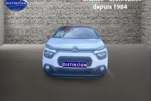 Vue frontale d'une Citroën C3 blanche avec toit rouge et calandre noire, stationnée devant un mur en briques.
