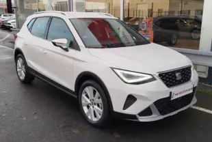 SEAT Arona blanc candy vue 3/4 avant droit, avec phares LED allumés et jantes alliage visibles.