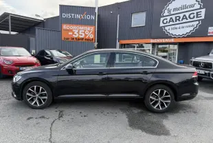 Profil côté gauche d'une Volkswagen Passat noire 2018 garée devant un garage avec jantes alliage visibles.