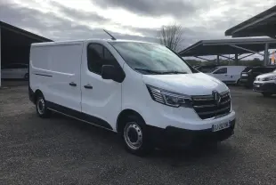 Renault Trafic Fourgon blanc vu en 3/4 avant droit sur parking, avec calandre noire et phares modernes.