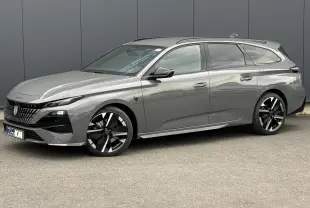 Peugeot 308 SW gris Sélénium vue 3/4 avant droit avec jantes bi-tons et barres de toit noires.
