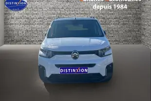 Vue frontale d'un Citroën Berlingo blanc 2025 avec logo chromé et pare-chocs noir dans un décor brique.