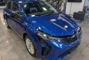 Vue 3/4 avant gauche de la Renault Clio V bleu Iron avec calandre noire et rétroviseurs noirs brillants en showroom.