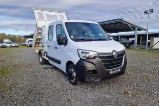 Renault Master blanc en 3/4 avant droit avec benne relevée et cabine double sur parking extérieur.