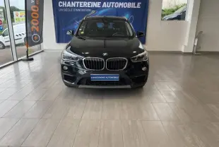 Vue frontale d'un BMW X1 sDrive16d noir Saphirschwarz, avec calandre double haricot et phares LED, en showroom.