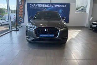 Vue frontale d'un DS3 Crossback gris Platinium avec calandre DS Wings et logo DS bien visibles en showroom.