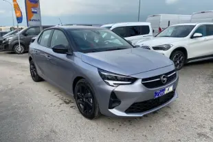 Opel Corsa gris magnetic vue 3/4 avant droit, jantes noires et toit bi-ton noir sur parking.