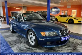 BMW Z3 bleu topaze en 3/4 avant droit dans un showroom, avec calandre chromée et jantes argentées.