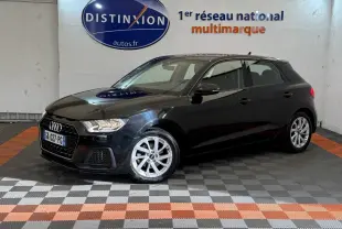 Audi A1 noire vue en 3/4 avant droit dans un showroom avec sol à damiers gris et orange.