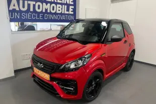 Vue 3/4 avant d'une Ligier JS50 50 Sport DCI rouge avec toit noir et jantes noires en showroom.