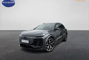 Audi Q6 e-tron gris nacré en 3/4 avant droit, avec jantes sport noires et étriers de frein rouges visibles.