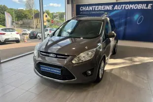 Ford Grand C-Max brun Palissandre vu de 3/4 avant droit dans un showroom avec calandre chromée et phares halogènes.