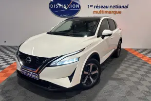 Nissan Qashqai blanc lunaire en 3/4 avant droit, avec toit panoramique et phares LED allumés dans un showroom.