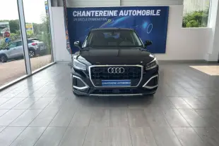 Audi Q2 noir brillant vue de face en intérieur, mettant en valeur sa calandre hexagonale et ses phares LED distinctifs.