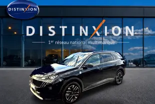 Peugeot 5008 Hybrid 145 GT noir en 3/4 avant droit, avec jantes alliage et vitres surteintées devant un showroom Distinxion.
