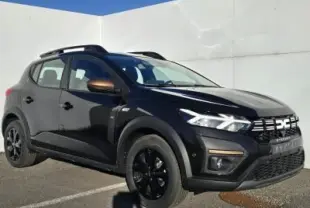 Dacia Sandero III Stepway noir nacré vue 3/4 avant droit avec barres de toit et jantes noires distinctives.