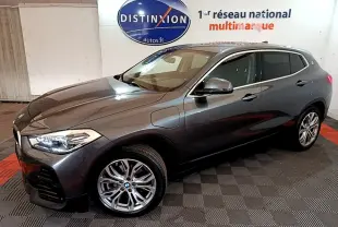 BMW X2 hybride rechargeable gris foncé vue 3/4 avant droit, jantes alliage et prises de recharge visibles