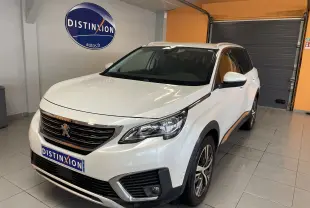 Peugeot 5008 blanc nacré en 3/4 avant droit dans un showroom avec logo Distinxion en arrière-plan.