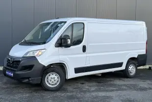 Vue 3/4 avant droit d’un Opel Movano Fourgon blanc 2024 avec pare-chocs noirs et porte latérale coulissante.