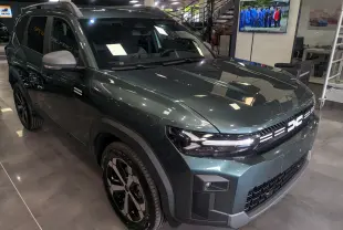 SUV Dacia Bigster vert cèdre en 3/4 avant droit, avec calandre lumineuse et jantes noires bicolores.