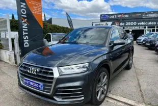 Audi Q5 gris foncé en 3/4 avant droit, finition S Line avec calandre distinctive et jantes alliage visibles.