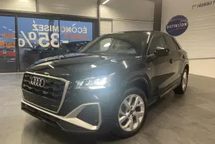 Audi Q2 noir métallisé en 3/4 avant droit avec phares allumés et jantes alliage 18 pouces style trapèze.