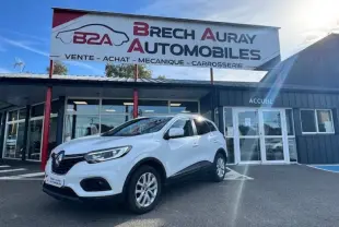 Renault Kadjar blanc en 3/4 avant droit devant un garage Brech Auray Automobiles par temps ensoleillé.