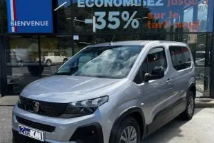 Peugeot Rifter gris foncé en 3/4 avant droit, garé devant une concession avec enseigne Distinxion visible.